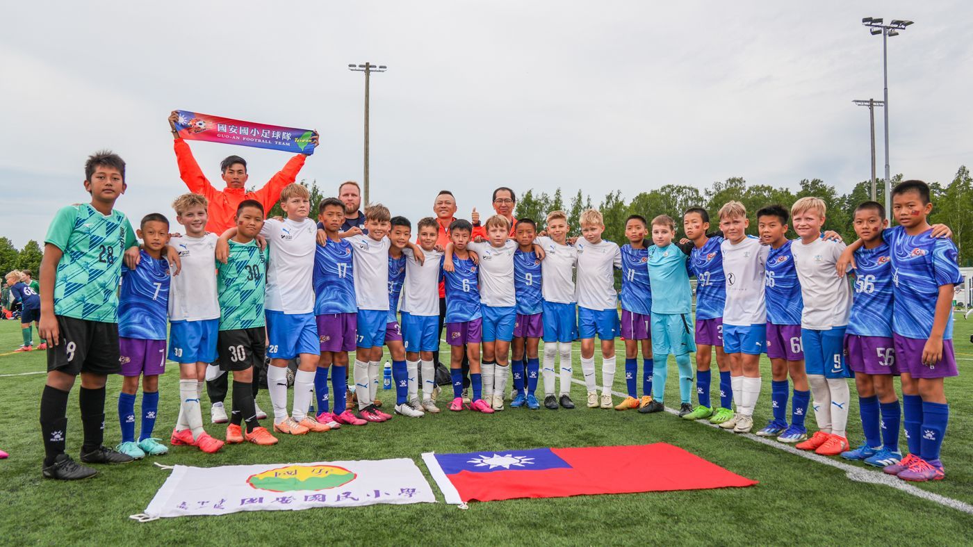 一群小男孩正在足球場上擺姿勢拍照。