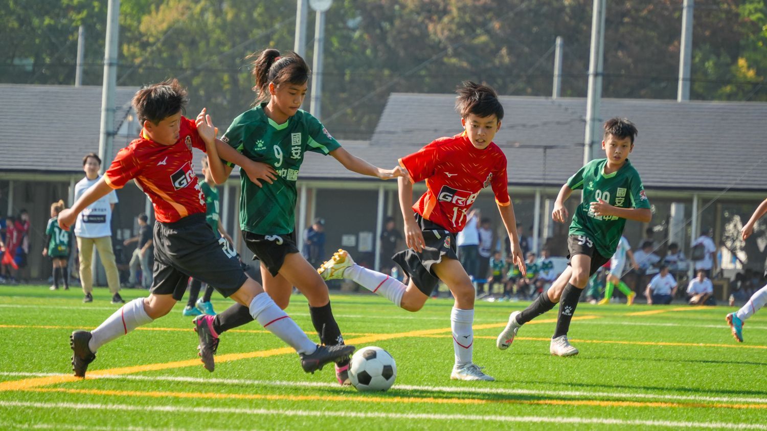 一群年輕女孩正在操場上踢足球。