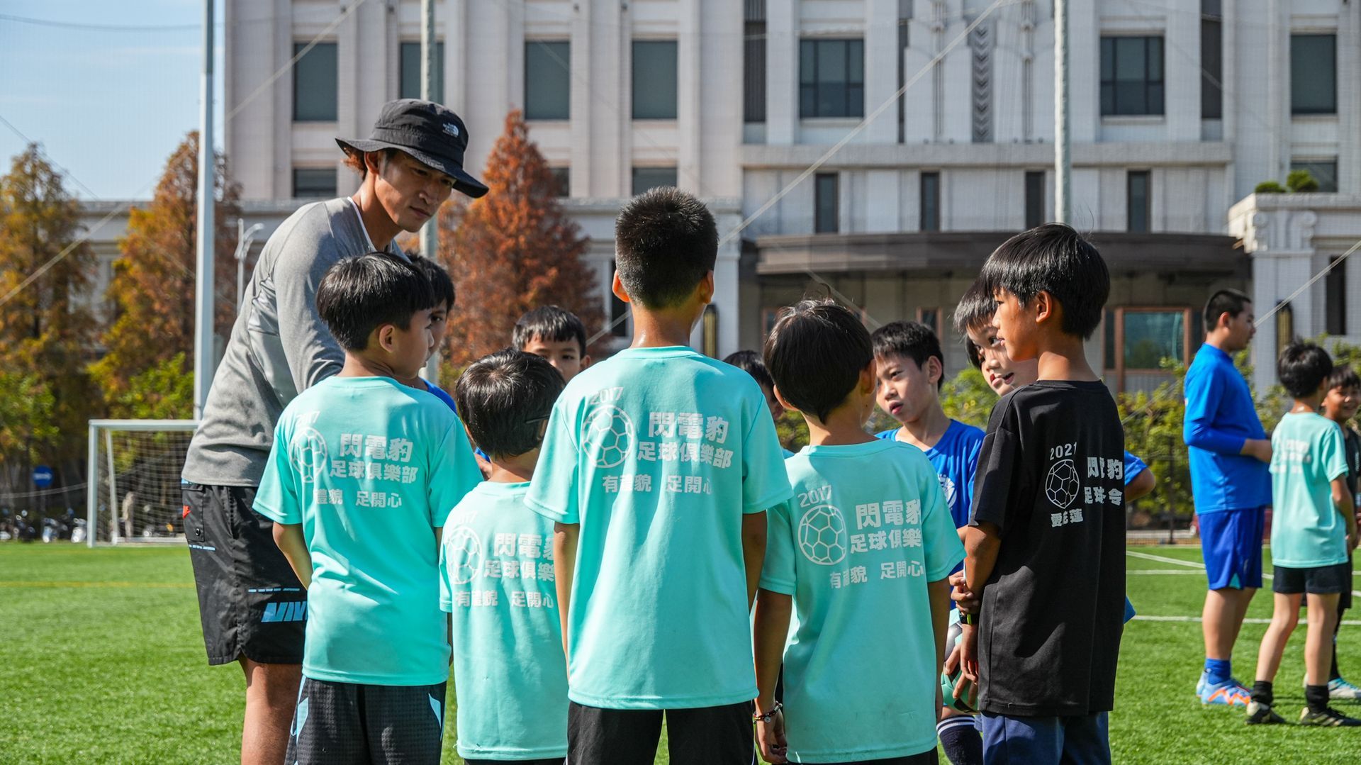 一群小男孩站在足球場上與教練交談。