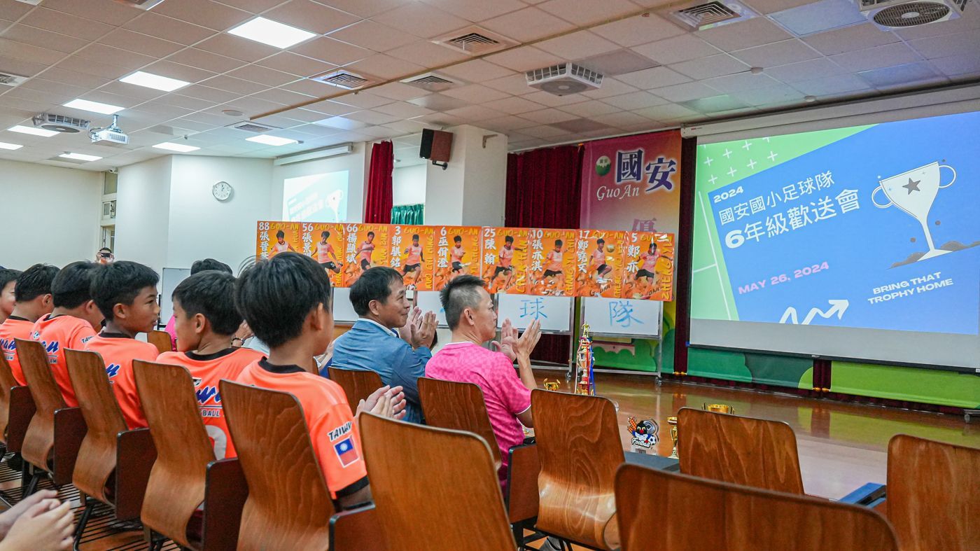 一群人坐在投影機螢幕前的椅子上。