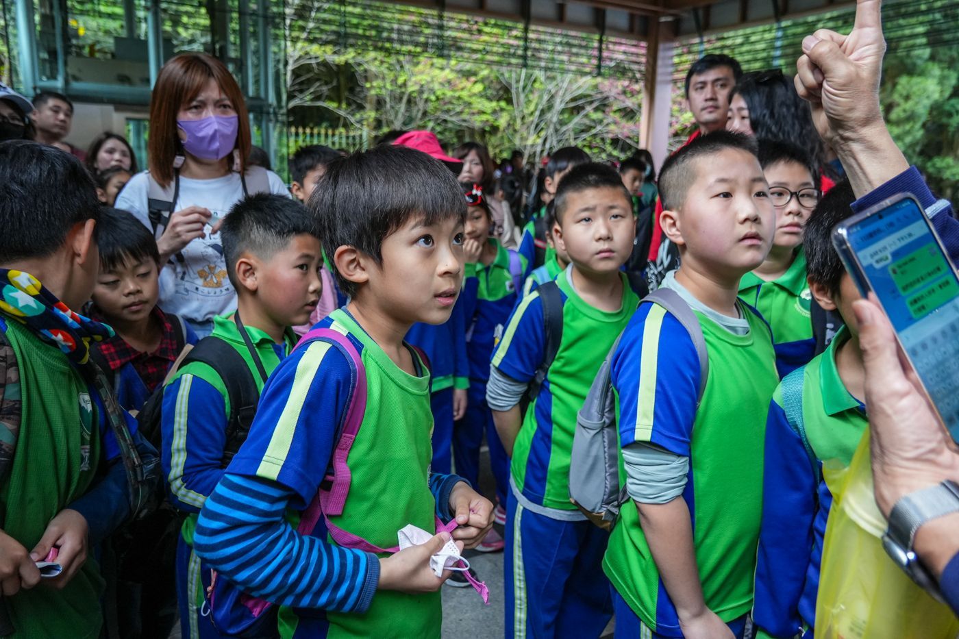 一群穿著綠色和藍色制服的孩子排成一排。