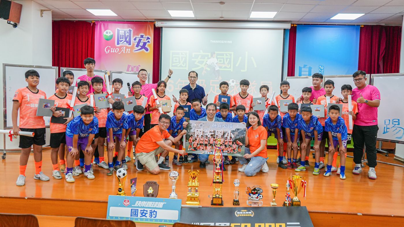 一群孩子正在一個放著獎盃的房間裡擺姿勢拍照。