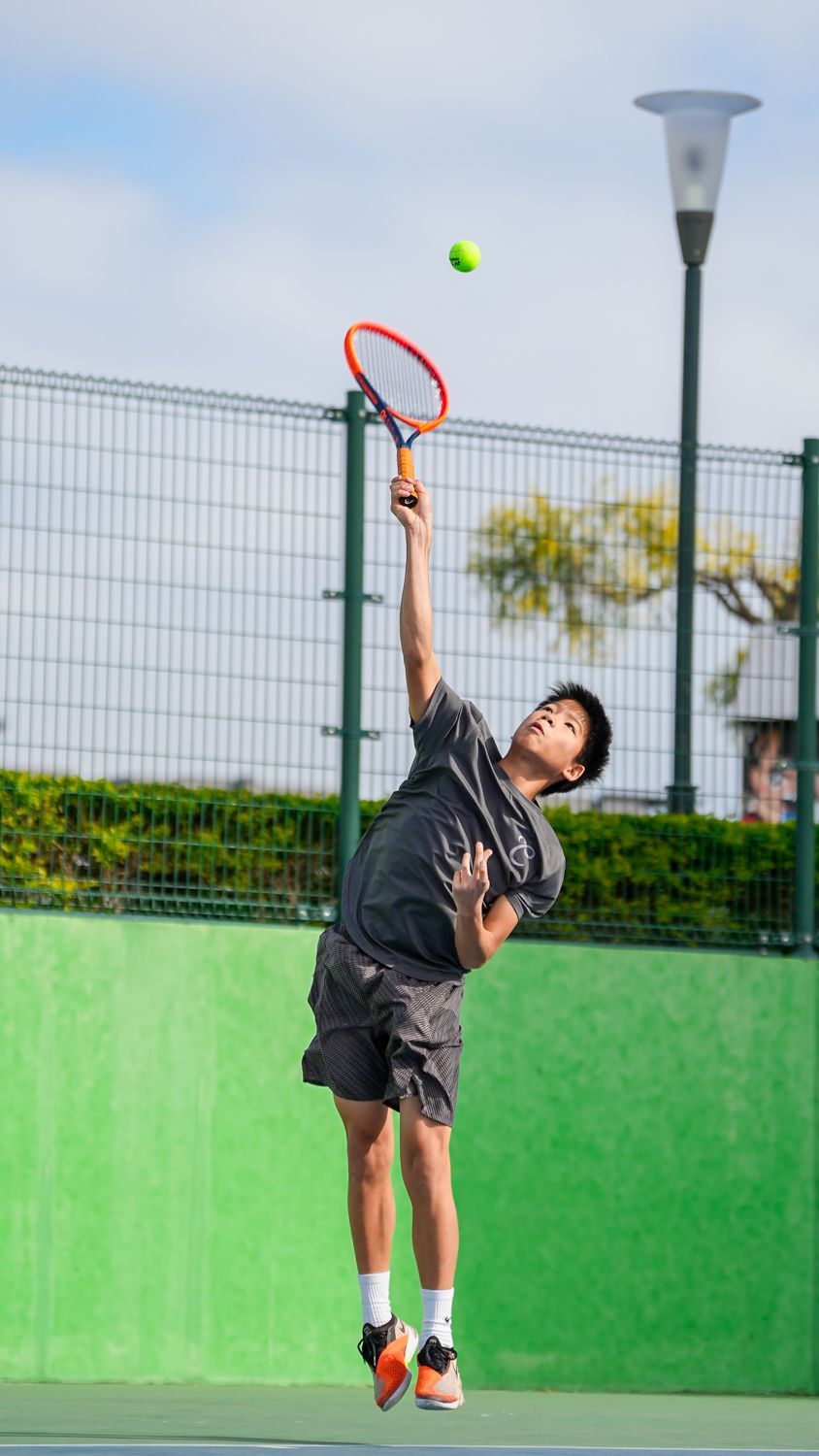 一名男子正在網球場上發網球。