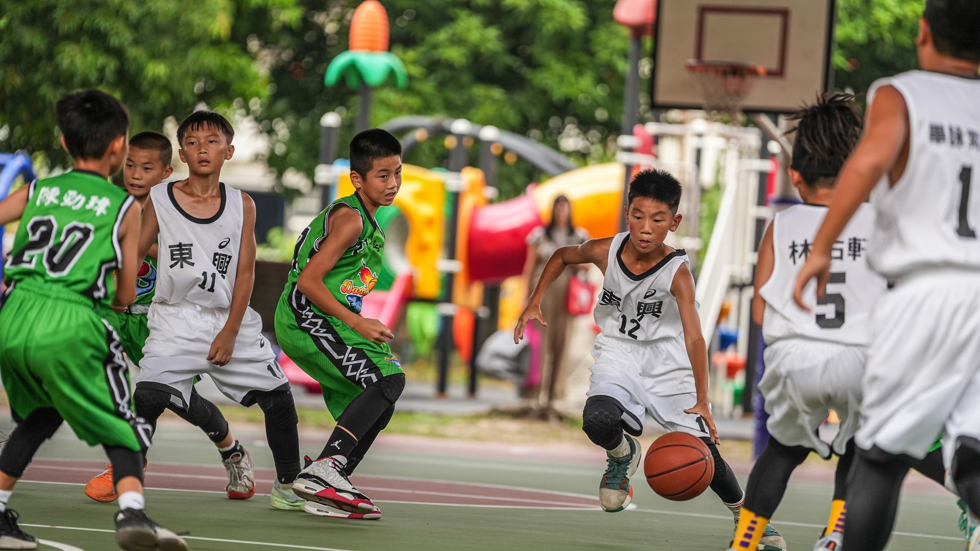 一個小男孩拿著一瓶柳橙汁站在自動販賣機前。