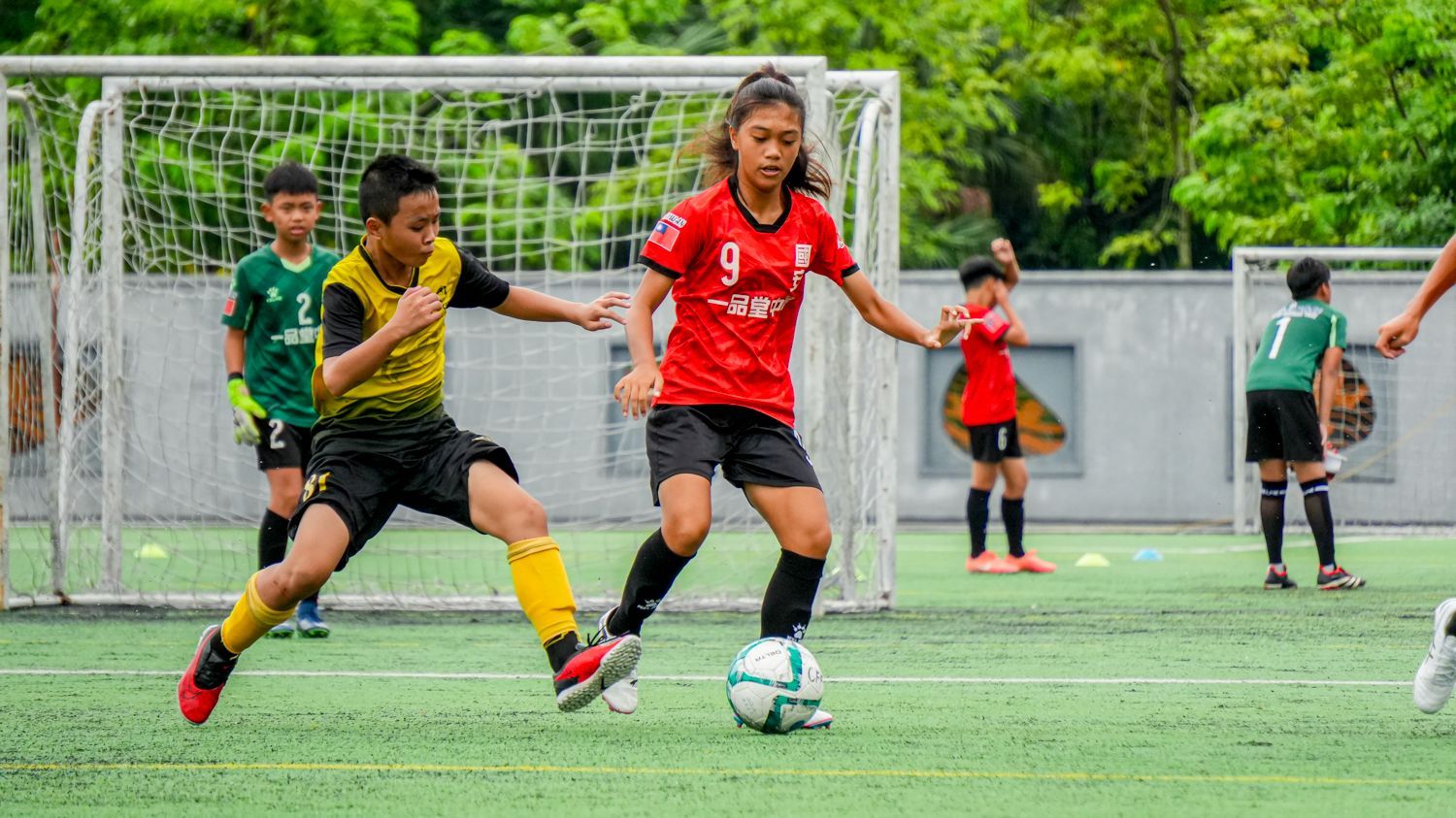 一群孩子正在操場上踢足球。