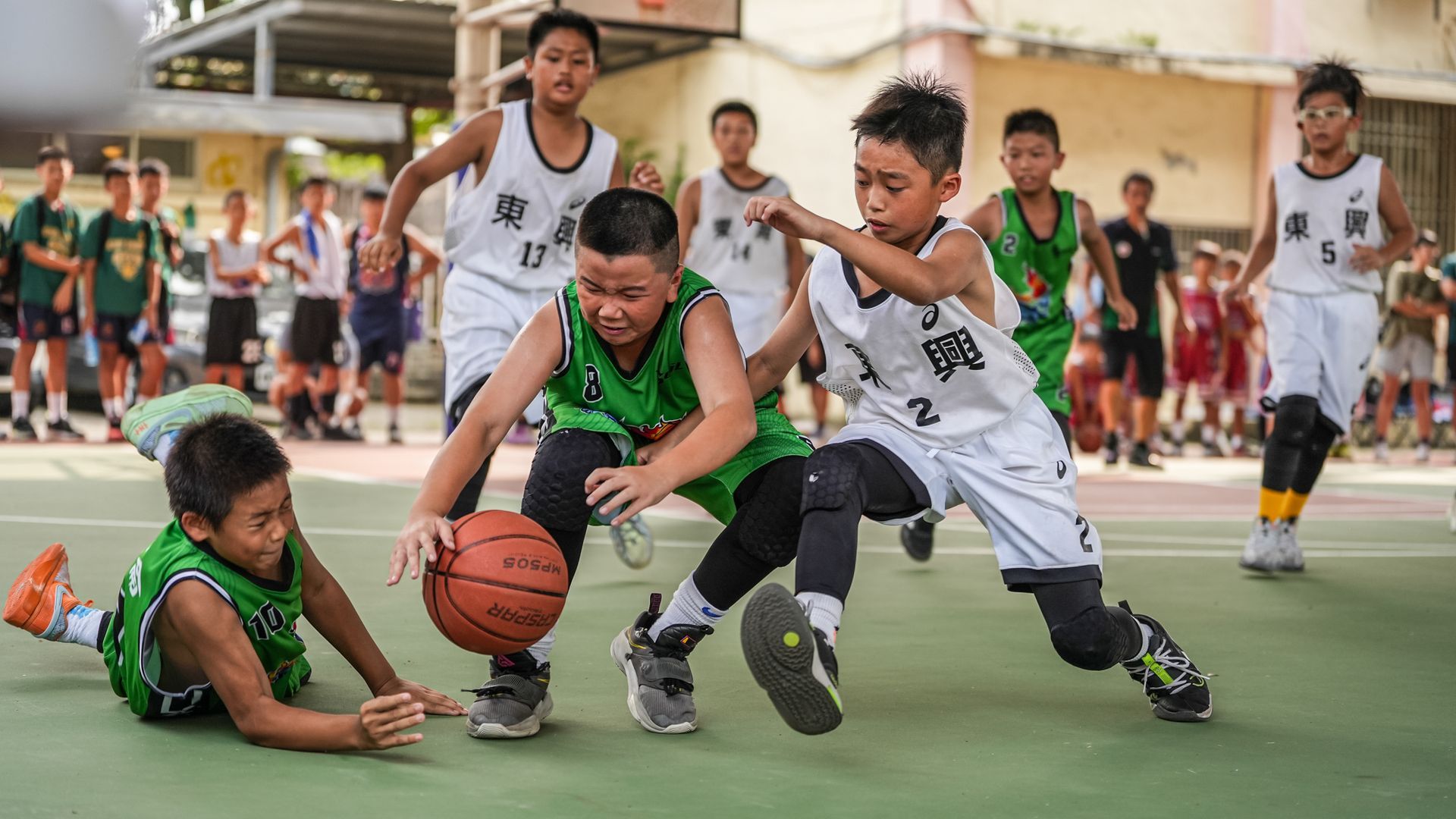 一群小男孩正在球場上打籃球。