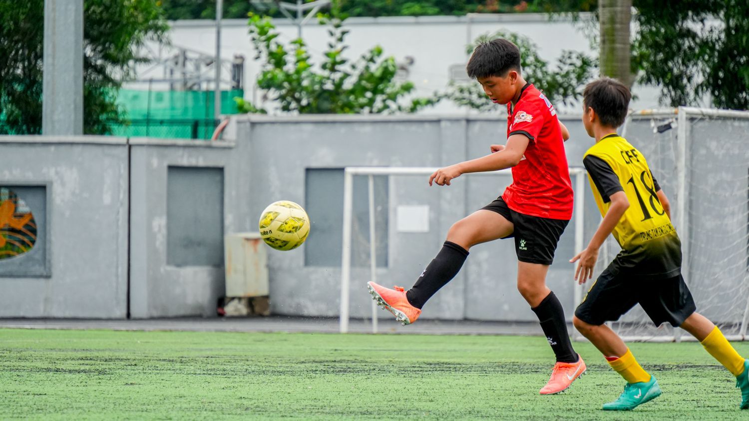 兩個小男孩正在操場上踢足球。