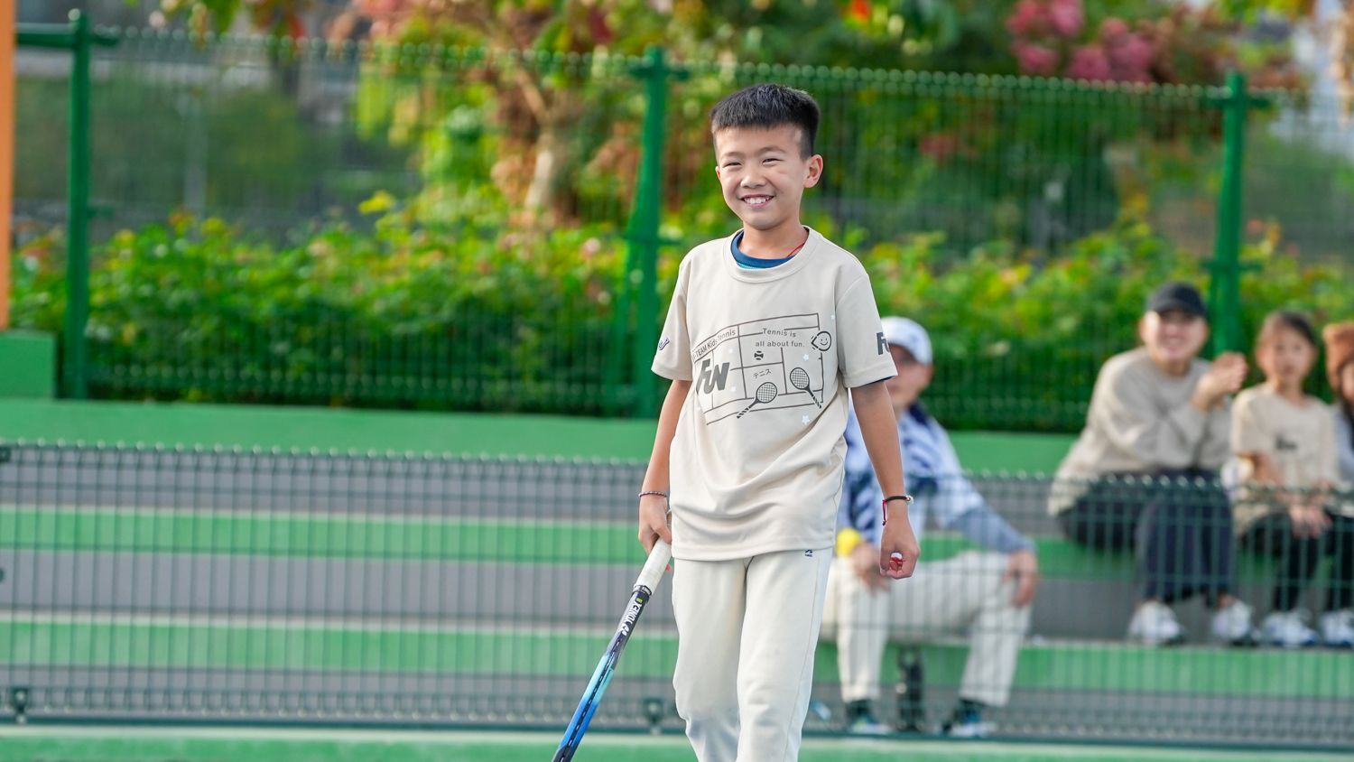 一個小男孩拿著網球拍在網球場上。