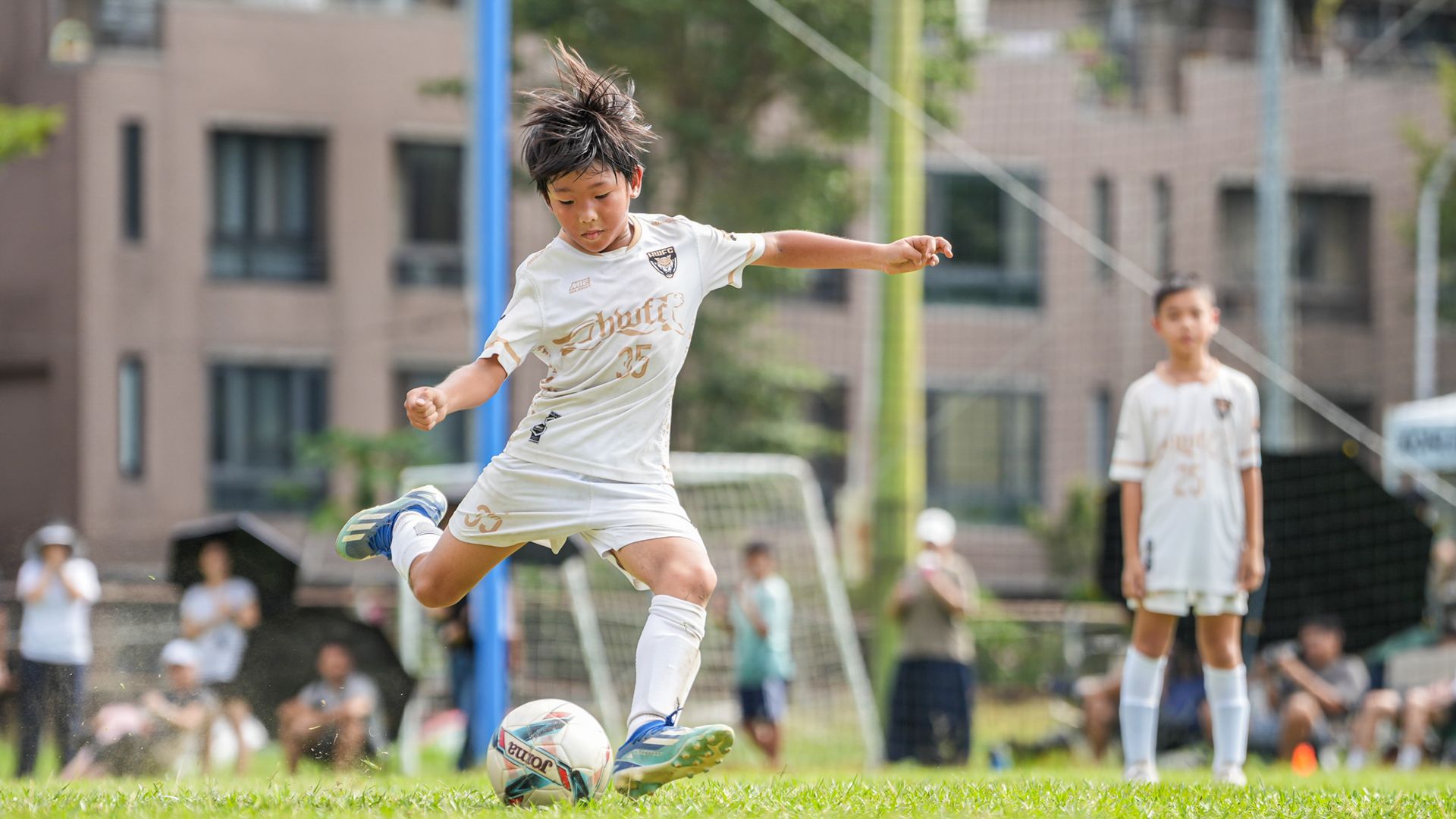 一個小男孩正在球場上踢足球。