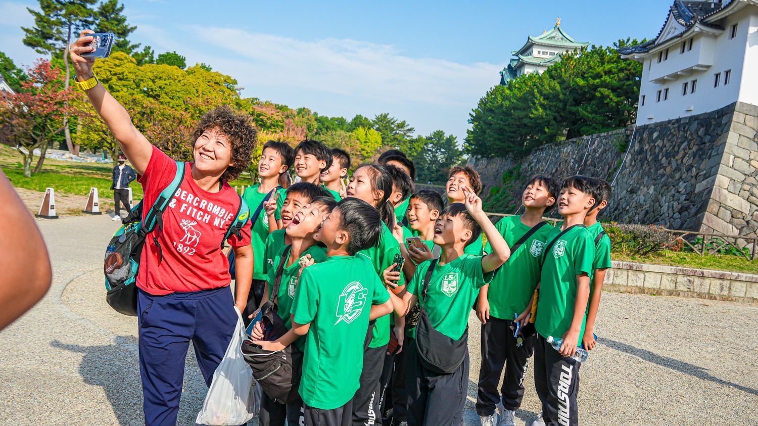 一名婦女正在與一群穿著綠色襯衫的孩子一起自拍。