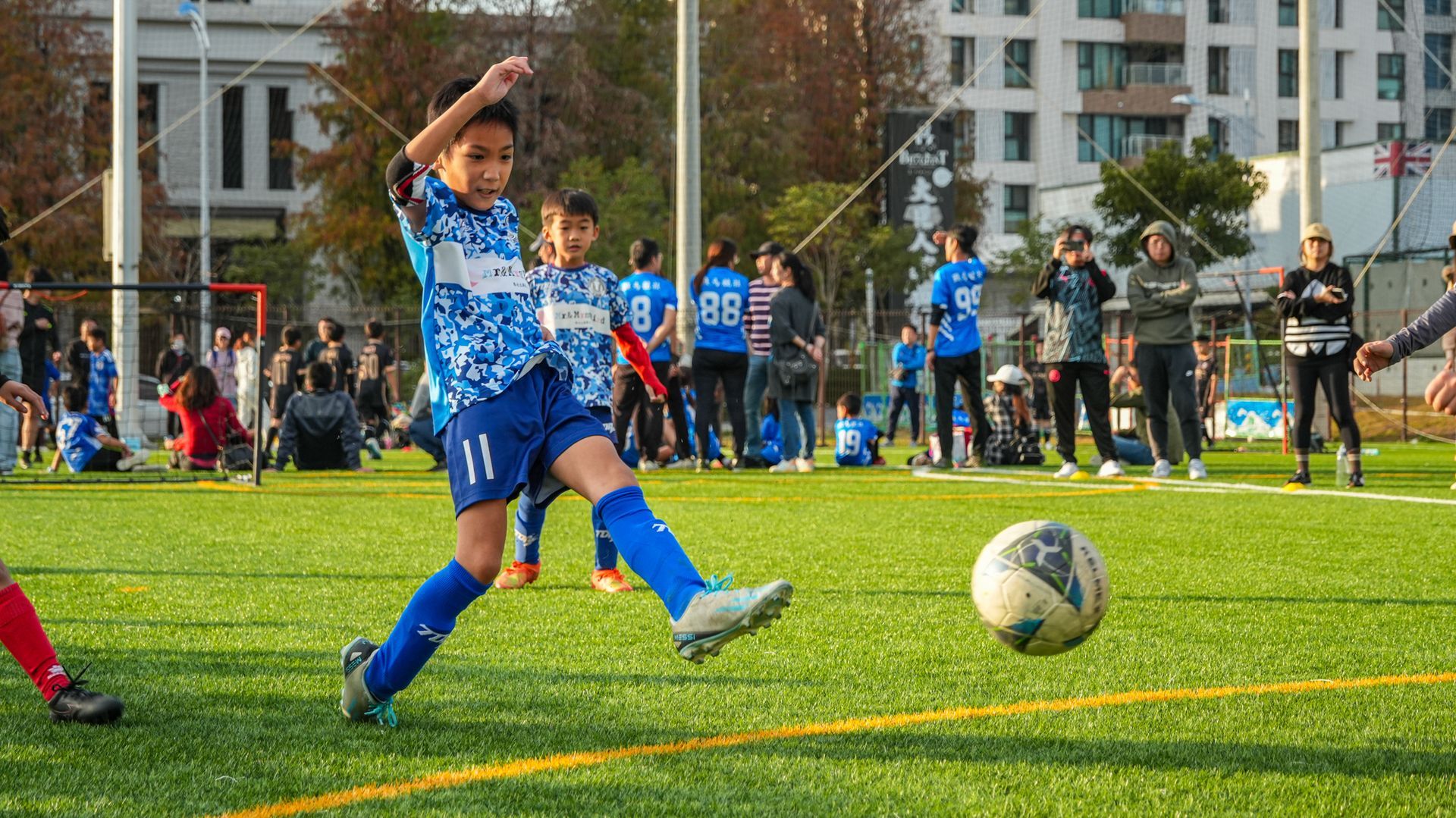 一個小男孩正在球場上踢足球。