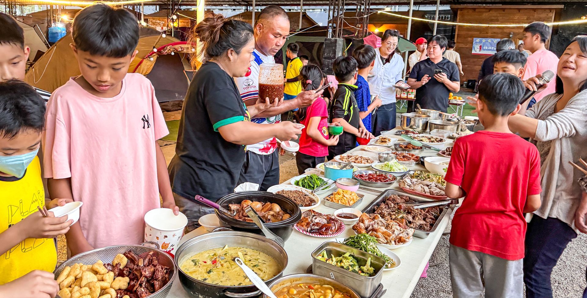 一群人圍著桌子站著吃食物。