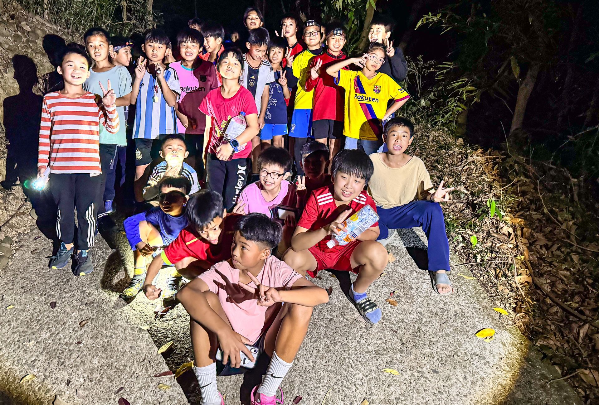 晚上，一群孩子在樹林裡擺姿勢拍照。