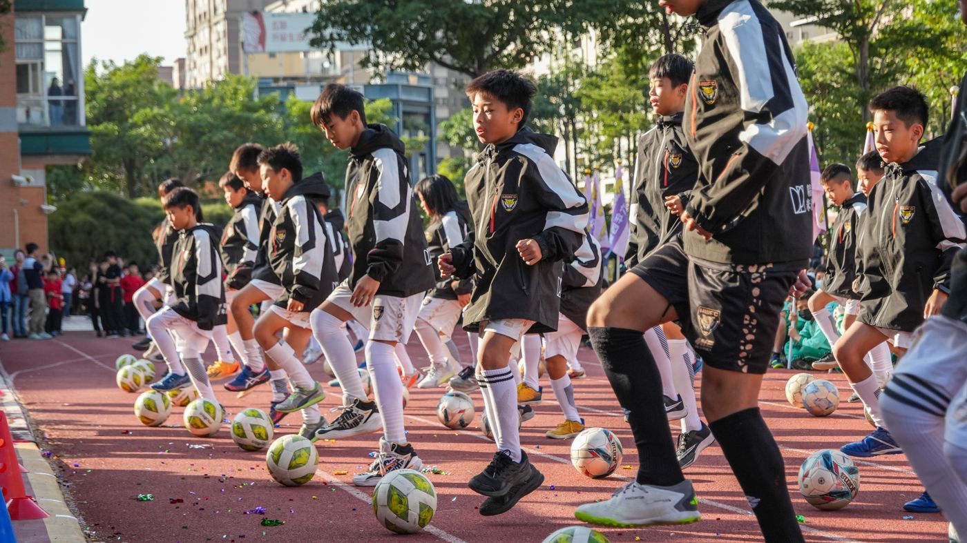 一群小男孩正在操場上踢足球。