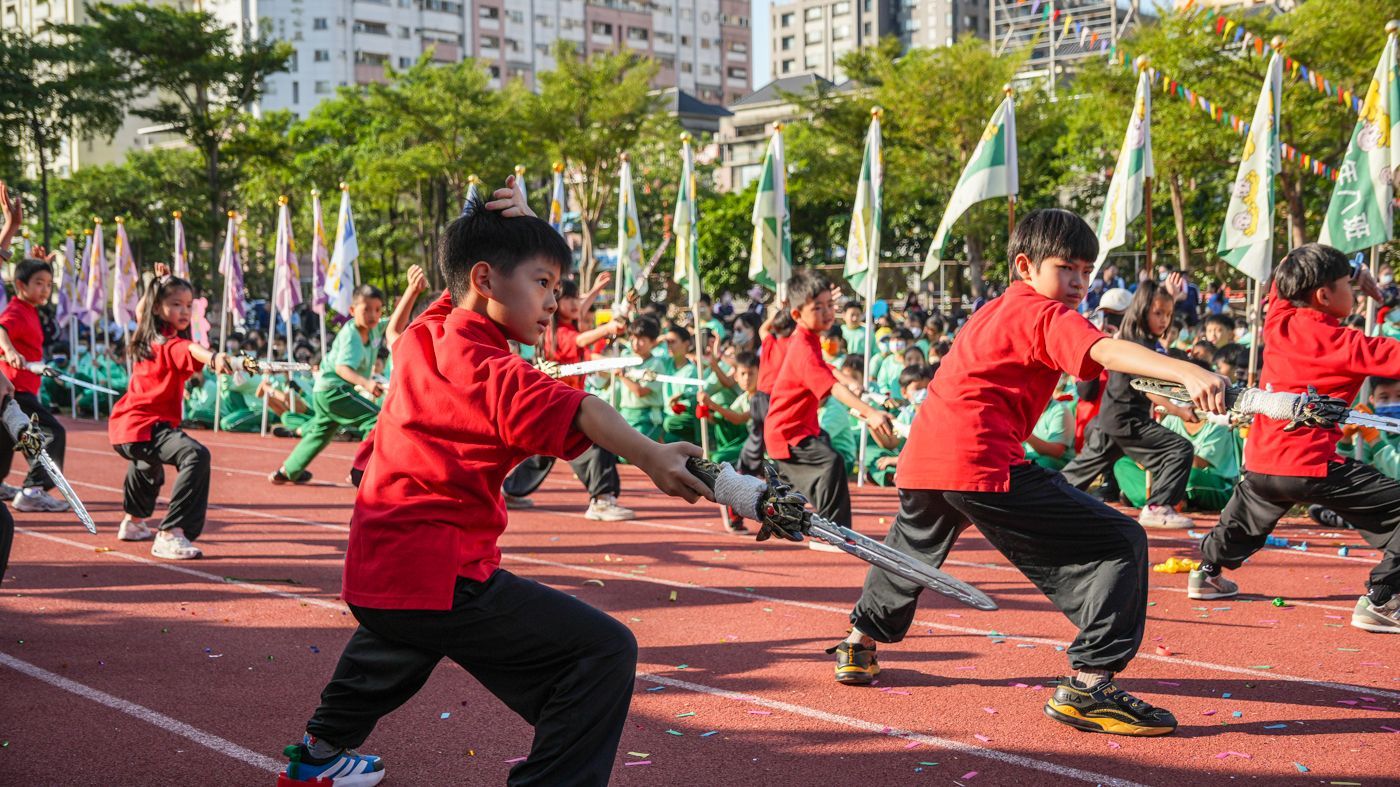 一群孩子正在跑道上練習武術。