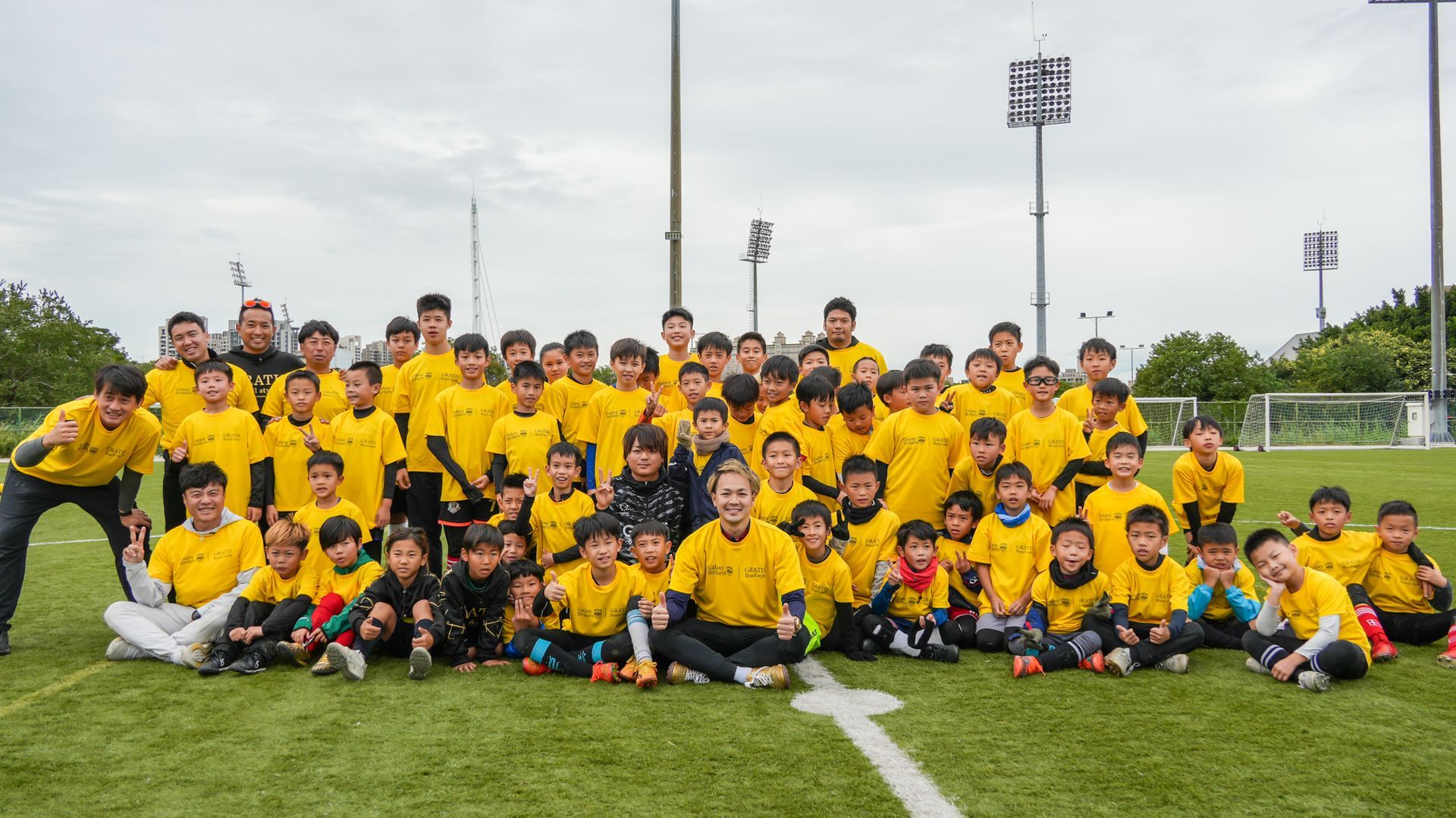 一大群孩子正在足球場上擺姿勢拍照。