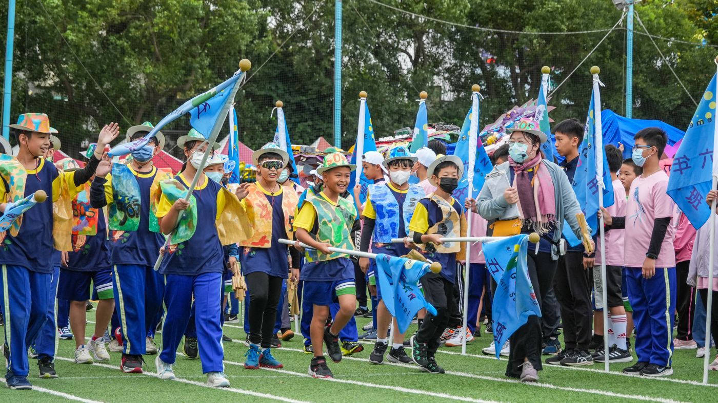 一群人舉著旗幟沿著田野行進。