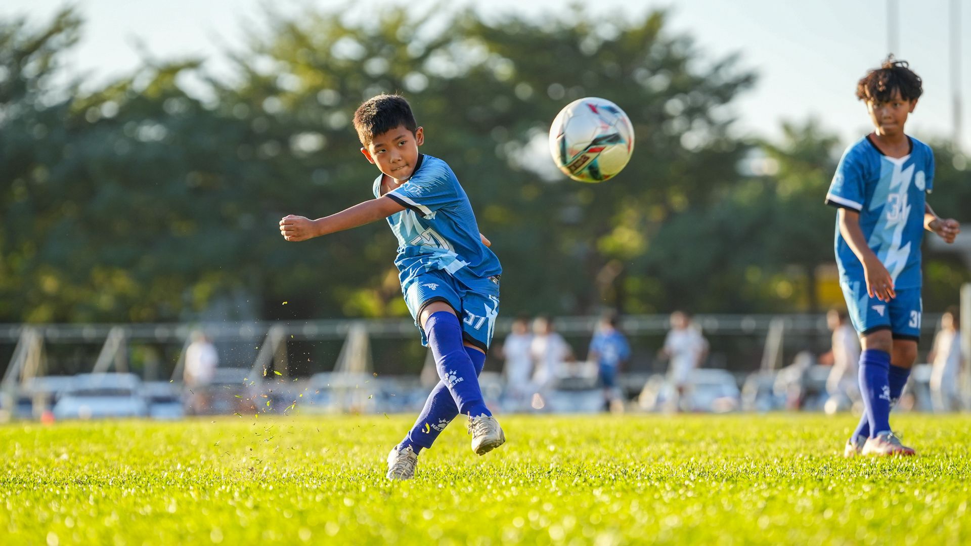 一個小男孩正在球場上踢足球。