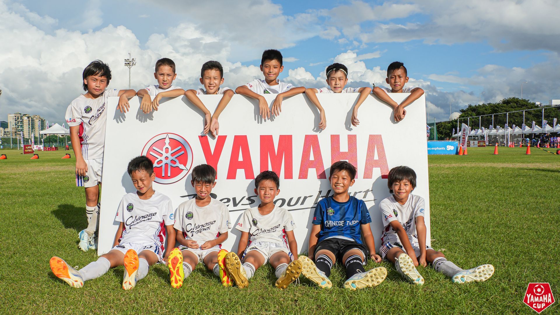 一群小男孩在雅馬哈標誌前擺姿勢拍照。