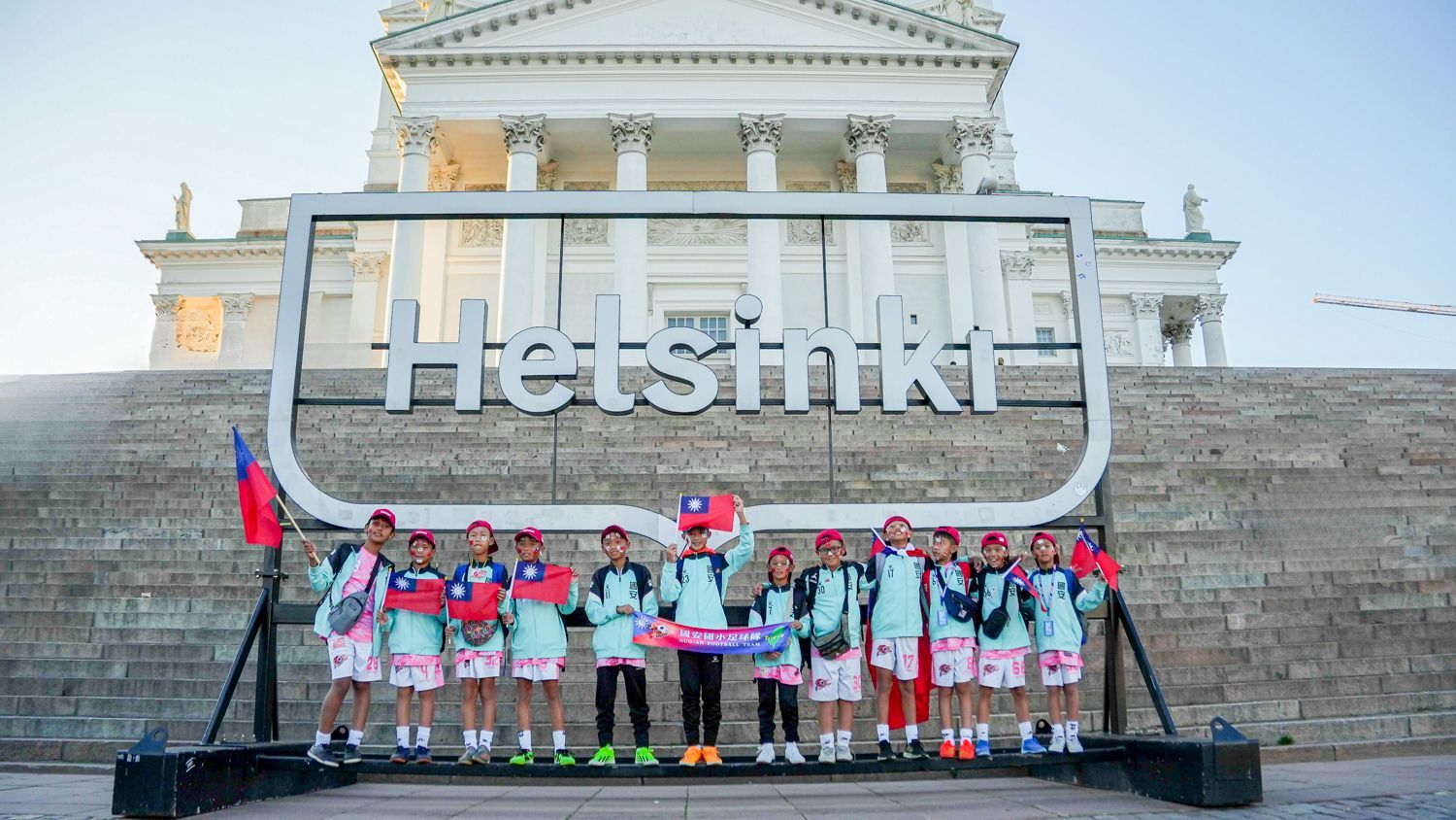 一群人站在寫著赫爾辛基的標誌前。