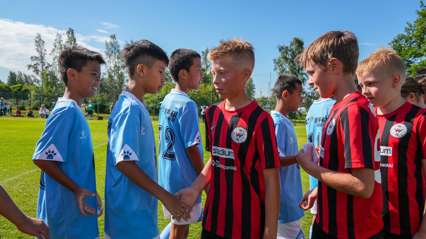一群小男孩正在足球場上握手。