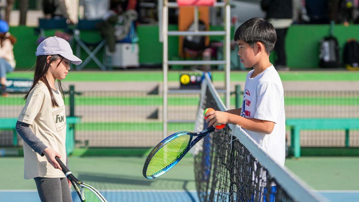 一個男孩和一個女孩正在網球場上打網球。