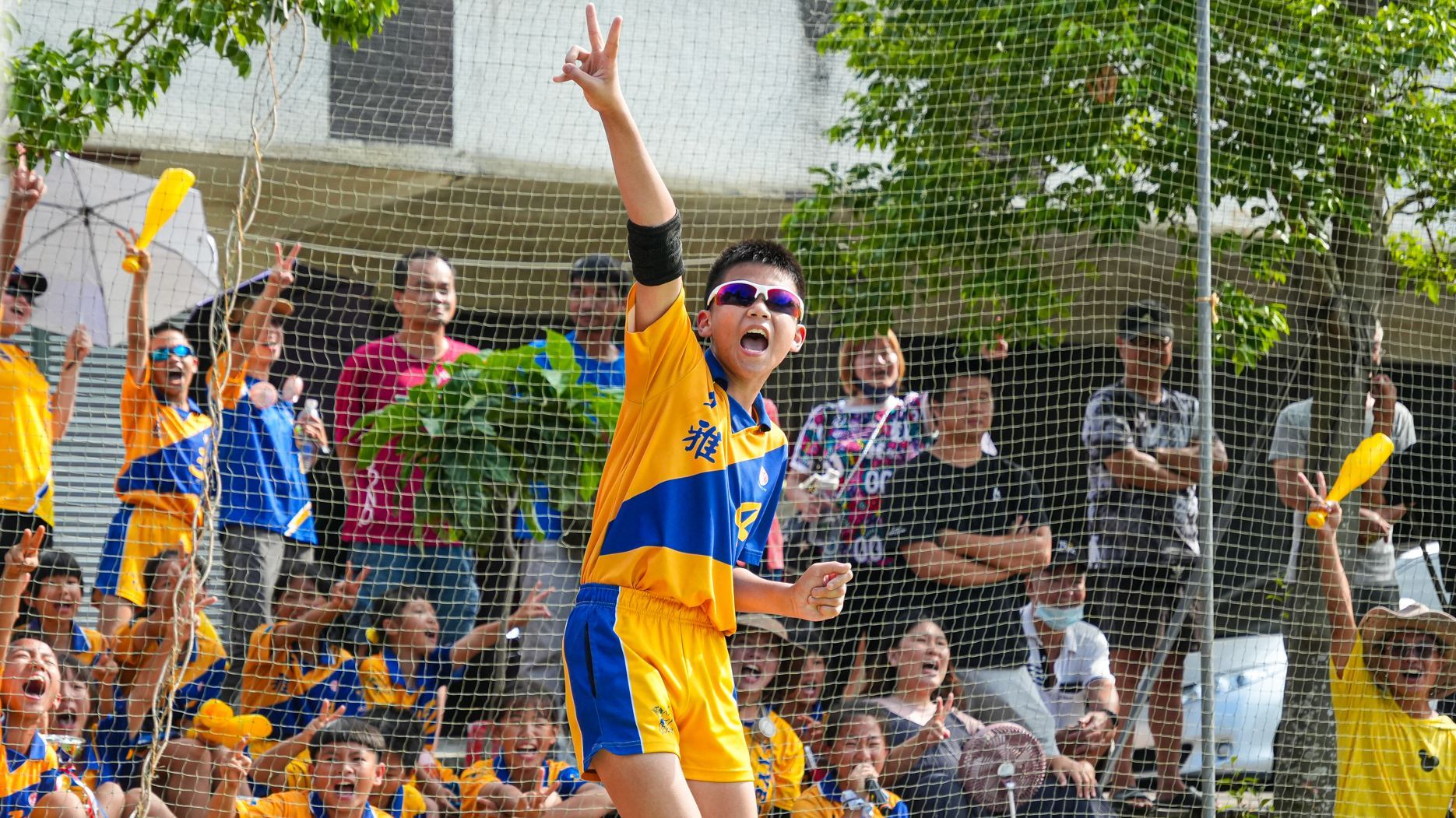 一個穿著黃色和藍色球衣的男孩站在一群人面前。