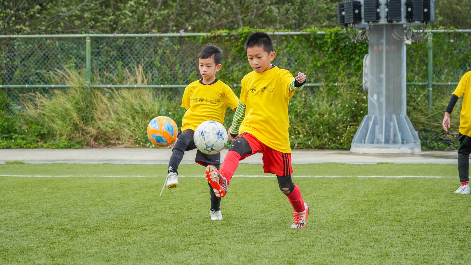 兩個小男孩正在操場上踢足球。