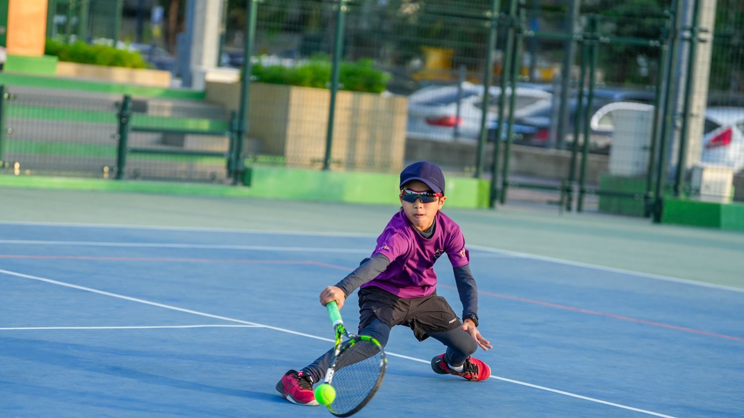 一個小男孩正在網球場上打網球。