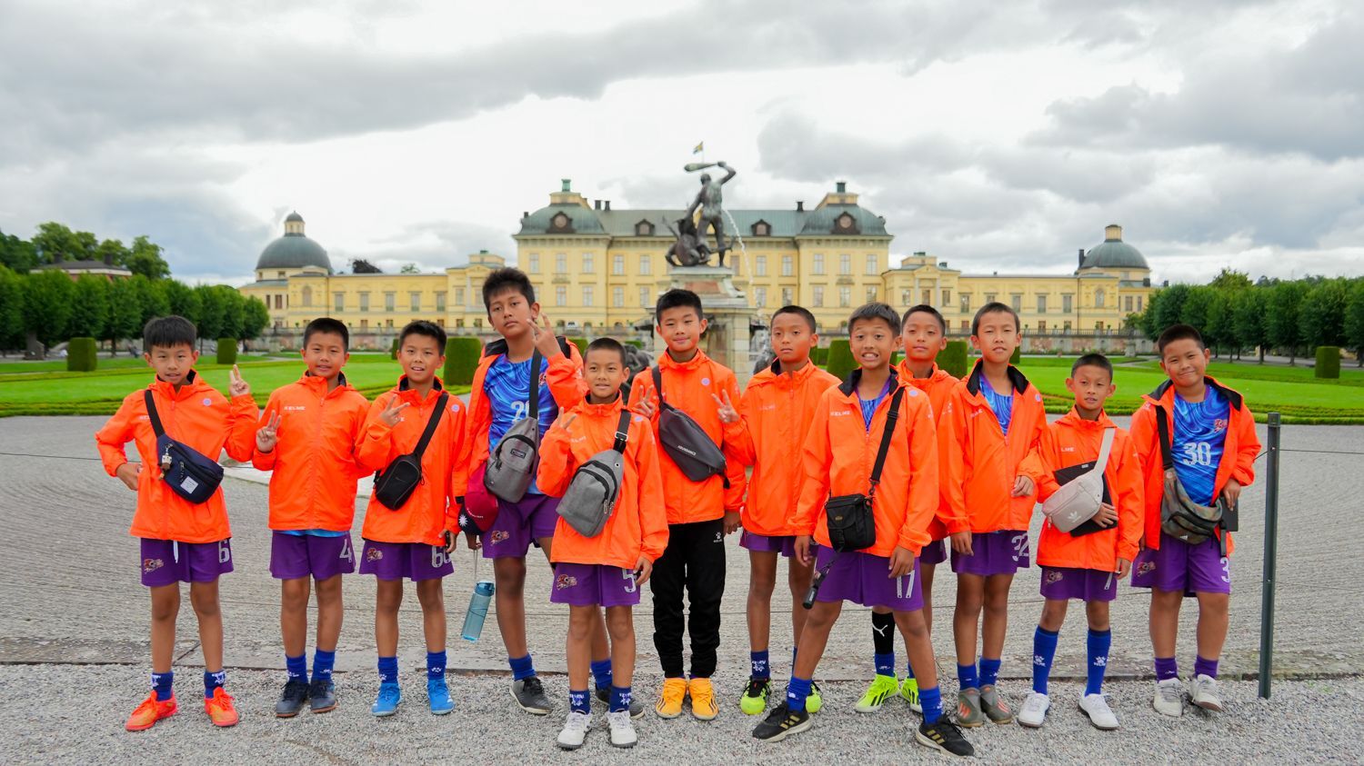 一群孩子在一棟大樓前擺姿勢拍照。