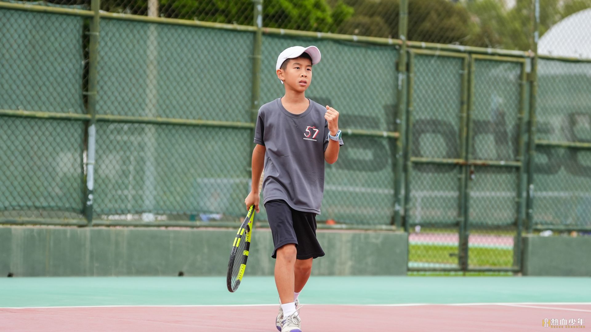 一個小男孩拿著網球拍在網球場上。