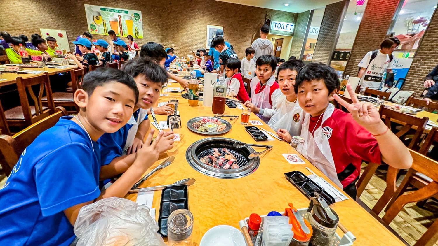 一群小男孩坐在一家餐廳的一張長桌旁。