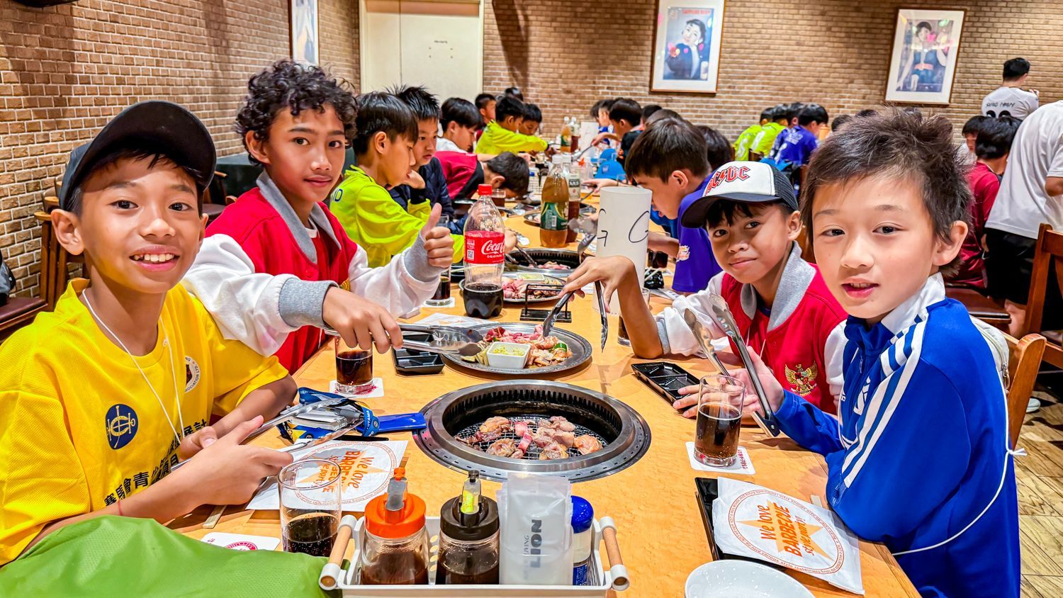 一群小男孩坐在一張長桌旁吃食物。