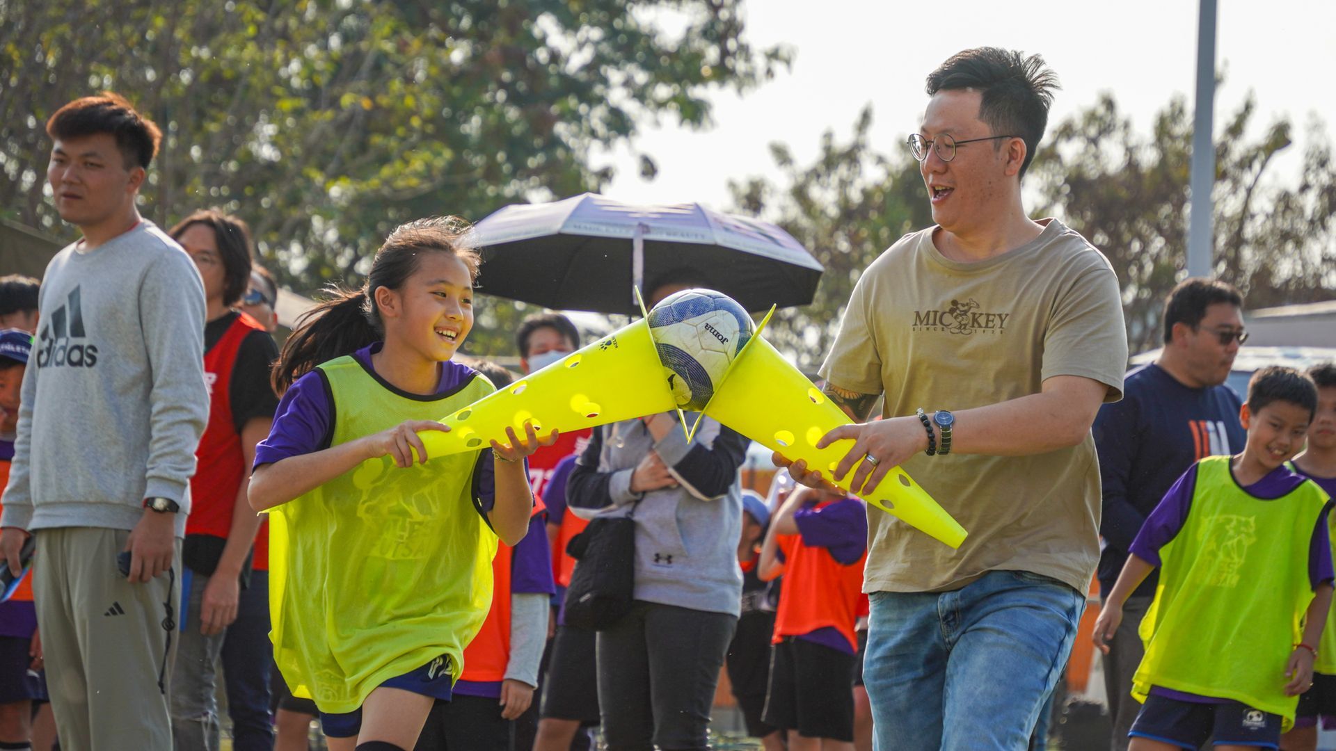 一個男人在一群孩子麵前拿著一個足球。