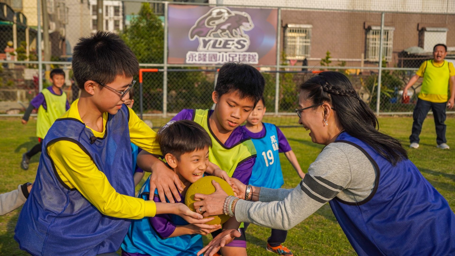 一群孩子和一個女人在田野上踢足球。