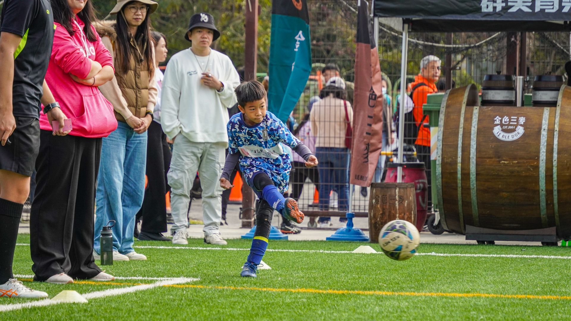 一個小男孩正在球場上踢足球。
