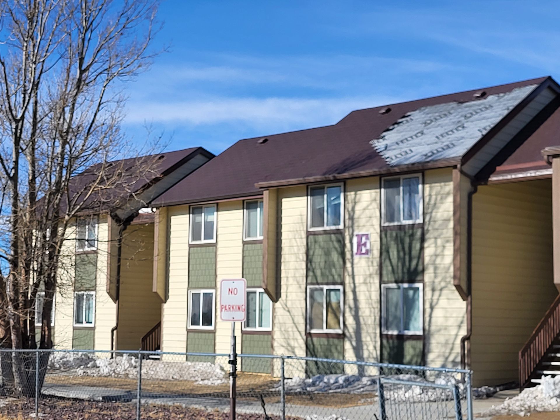 Apartment building with brown roof, tan and green siding, and 