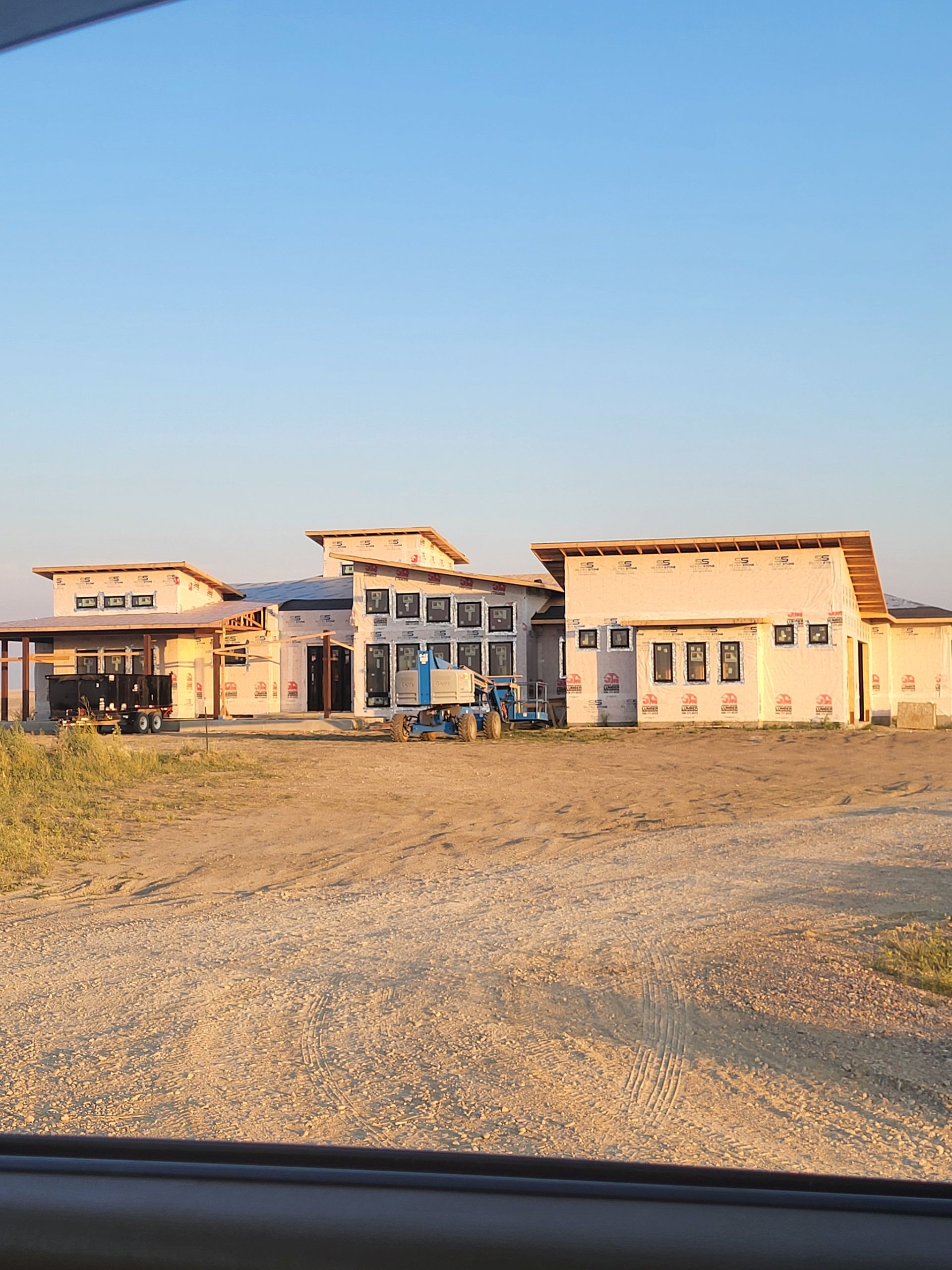 Construction site of a modern light pink building under a clear blue sky.