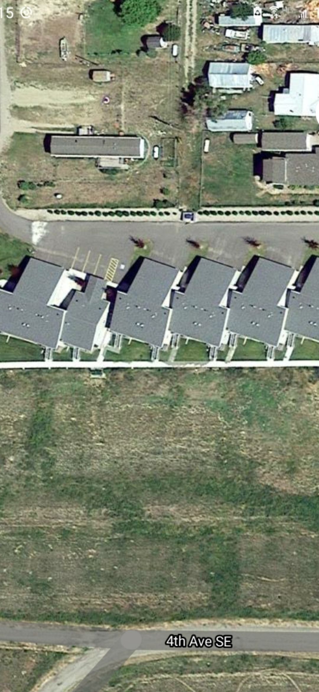 Aerial view of townhouses in a row, with a grassy area and road in the foreground.