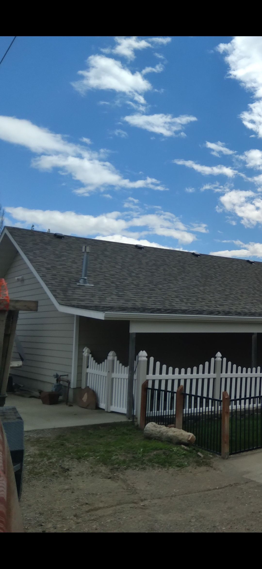 A house with a white picket fence decorated with ghosts under a cloudy blue sky.