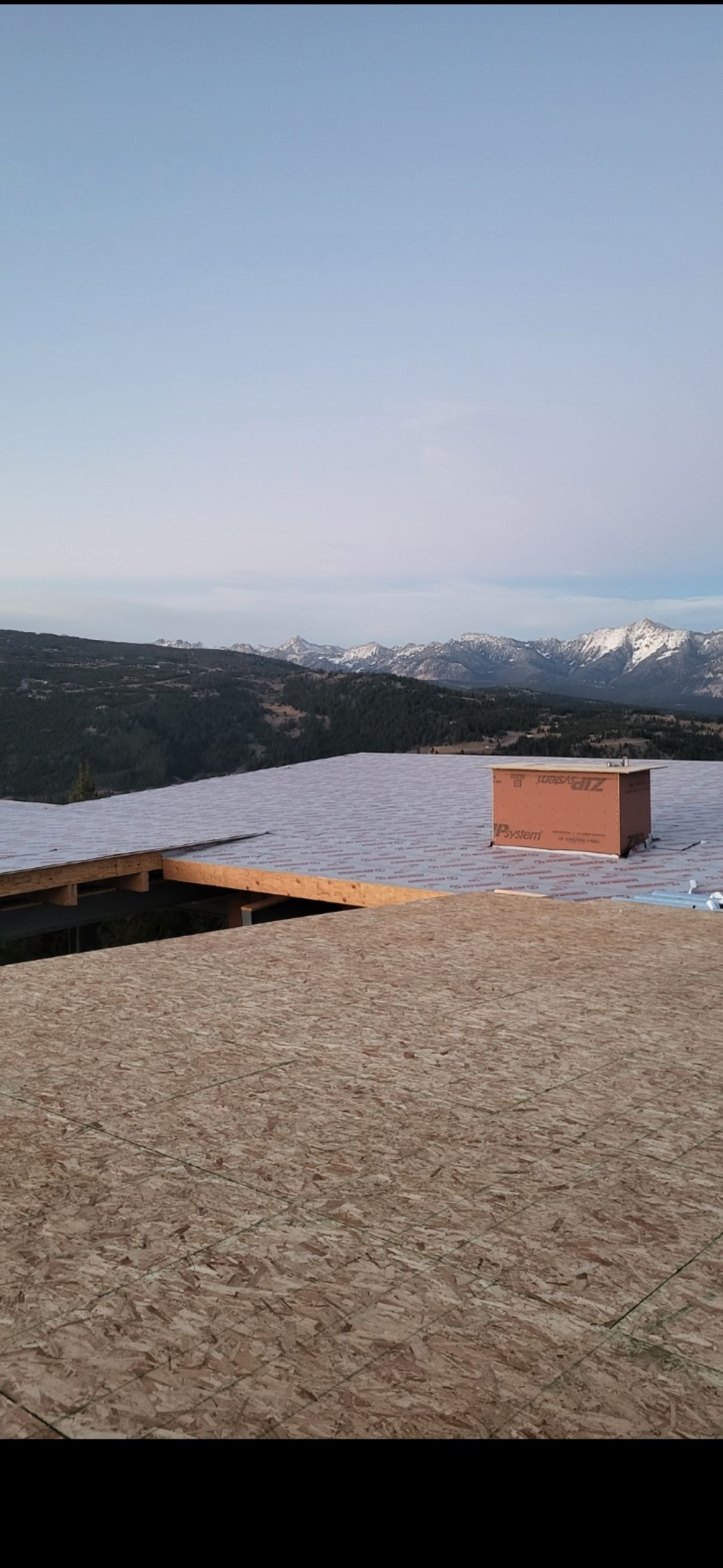 Snow-covered landscape with mountains in the background and a brown box. Sky is visible.