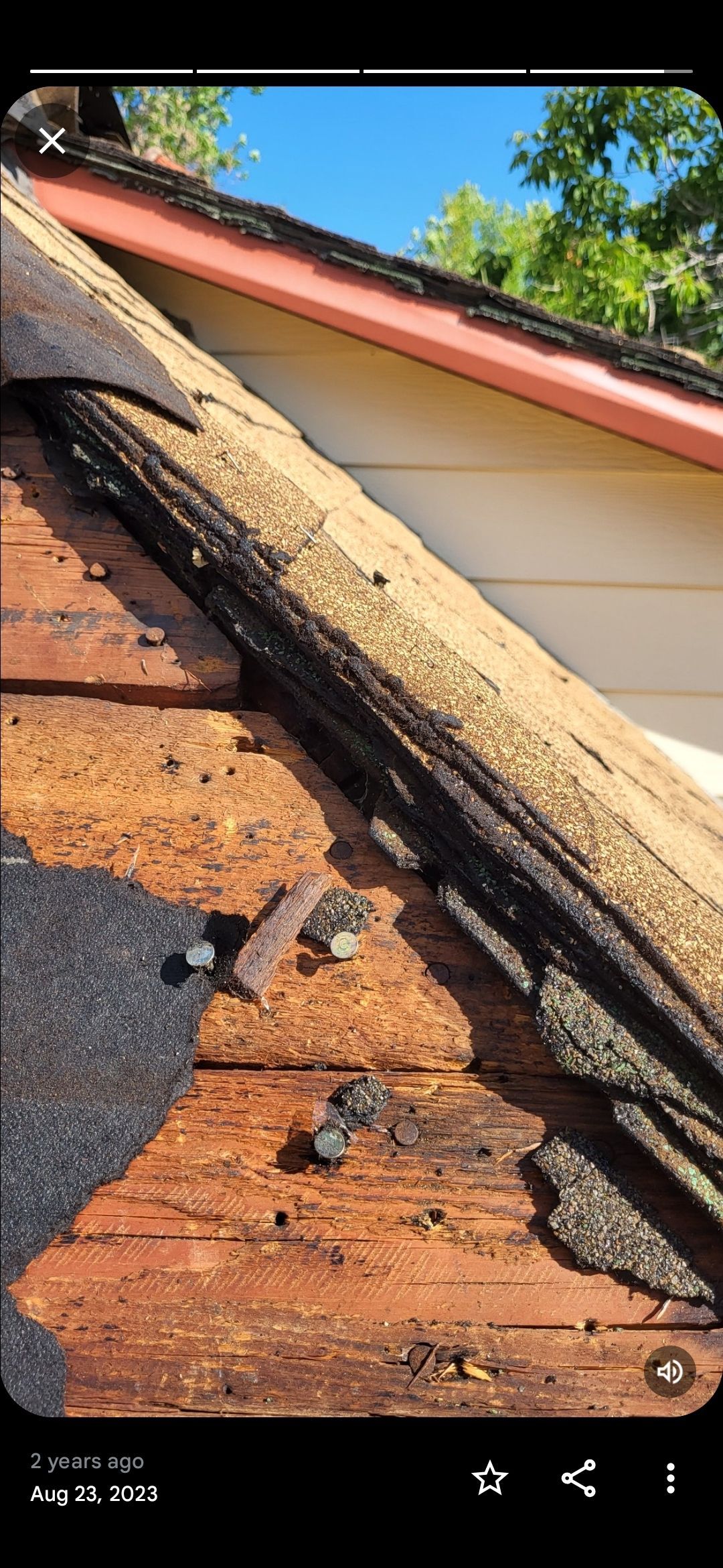 Damaged roof with missing shingles exposing weathered wooden boards and nails.