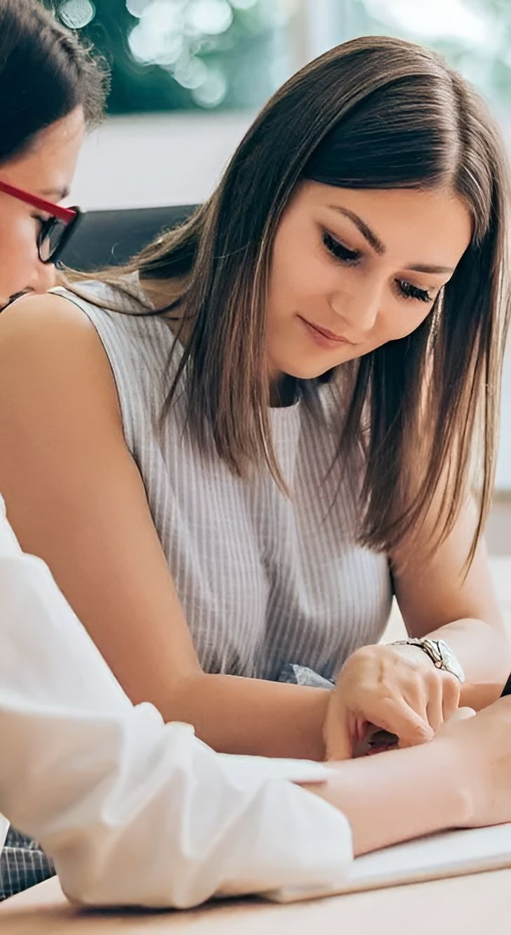 Two Women Are Sitting at a Table With a Laptop — Tony Talks in Redcliffe, QLD