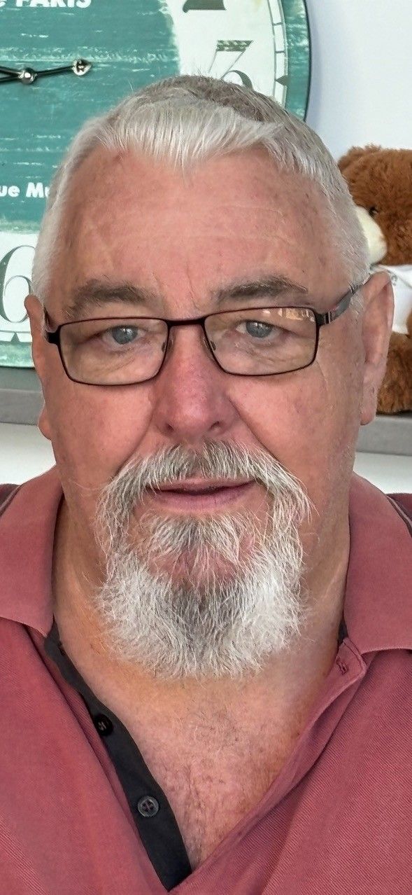 A man with a beard and glasses is wearing a red shirt.