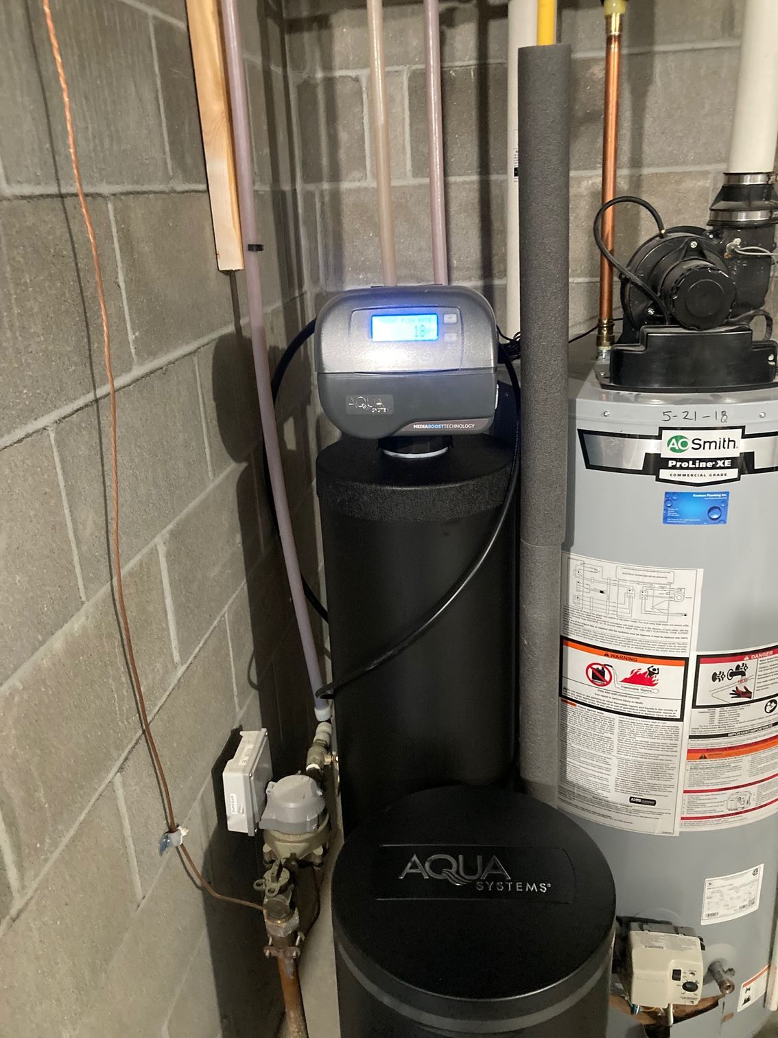 Water softener and water heater in a basement setting.