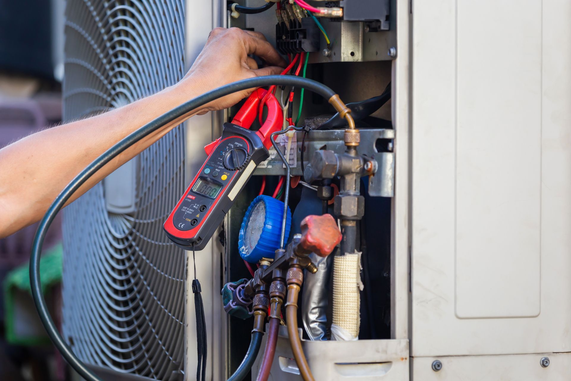 A male technician checking and fixing a modern air conditioning system.