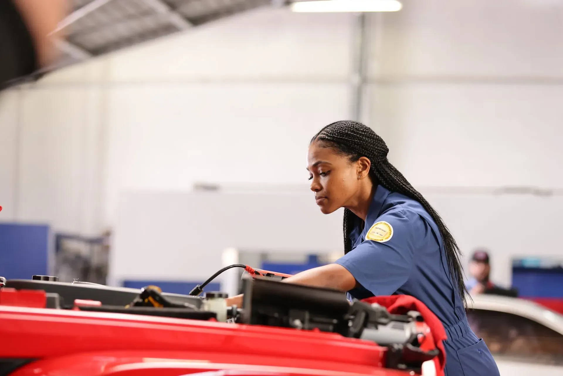 A woman is working on a red car in a garage.