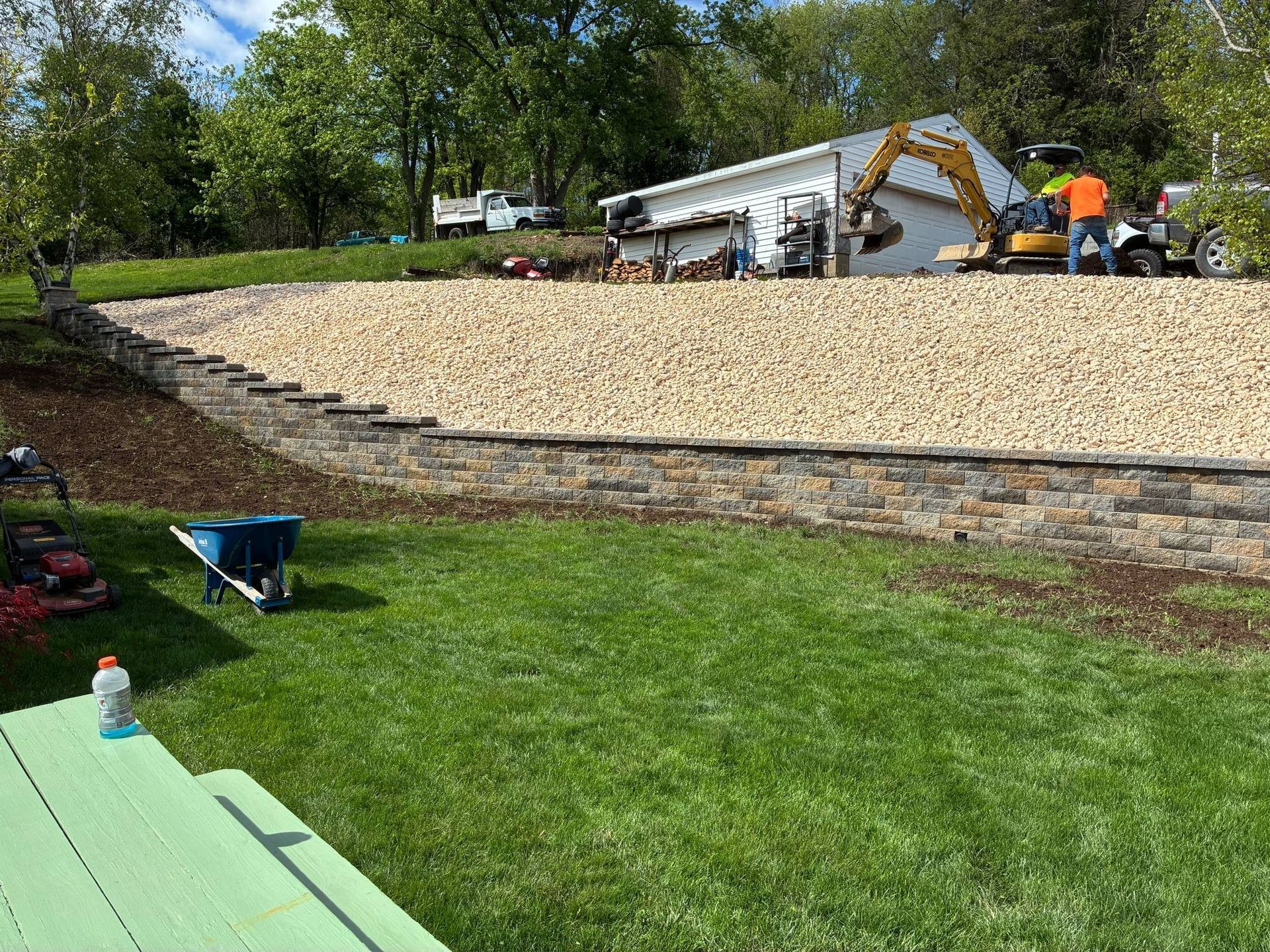 A wheelbarrow is sitting in the grass in front of a house.