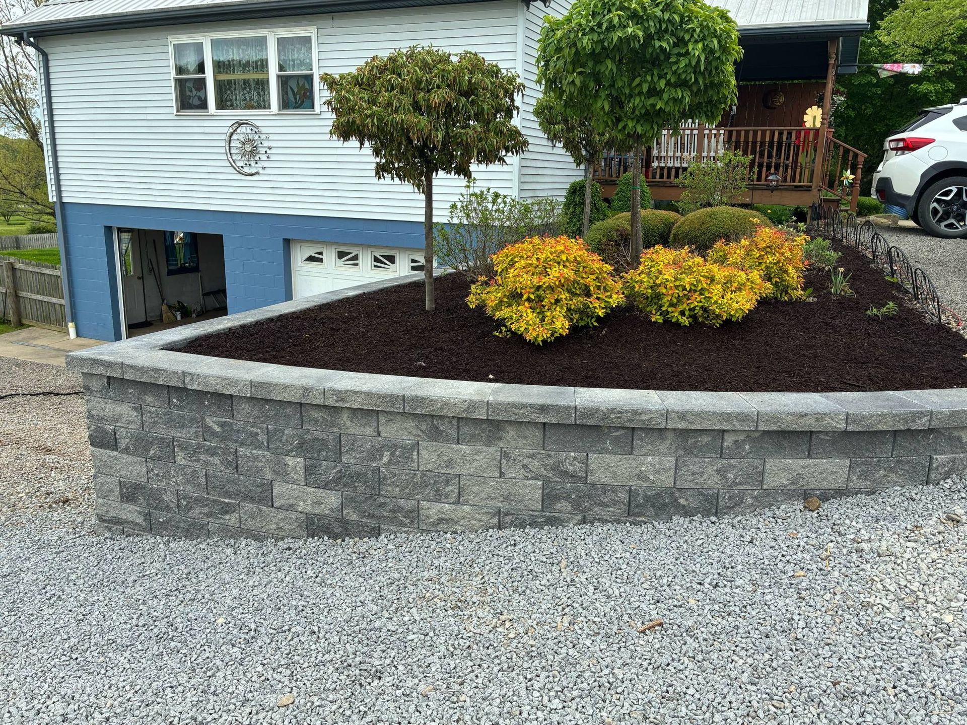 A car is parked in front of a house with a garden in front of it.