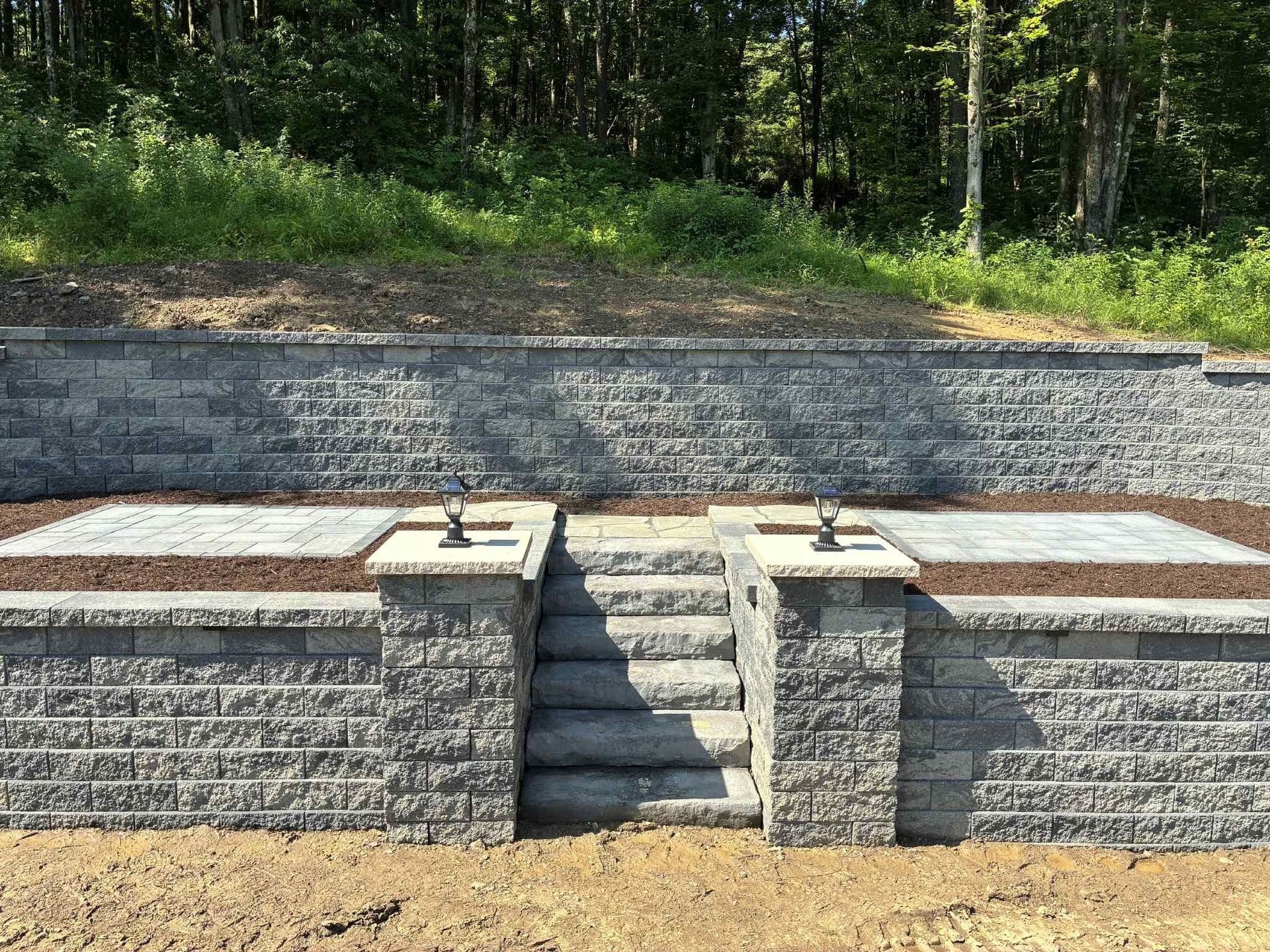 A brick wall with stairs leading up to it in the middle of a field.